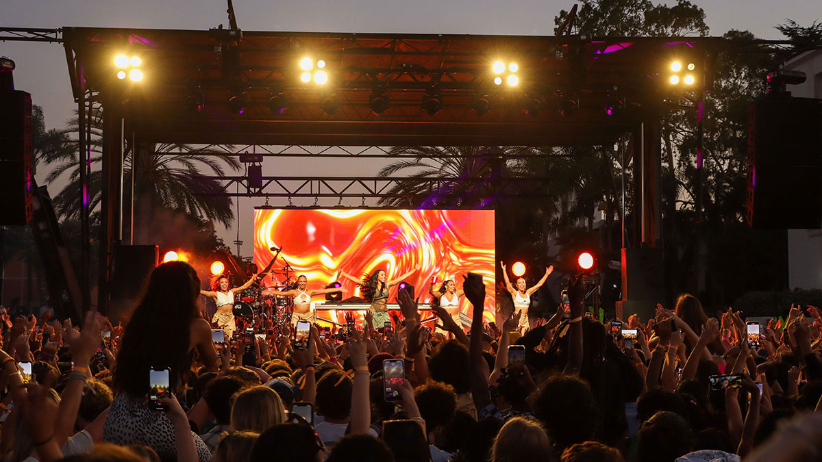 performers on stage with a big crowd of students in the foreground